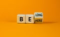 Be here belong symbol. Turned a cube and changed words `be here` to `belong`. Beautiful orange background. Business, belonging