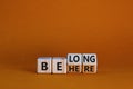 Be here belong symbol. Turned cubes and changed words `be here` to `belong`. Beautiful orange background. Business, belonging