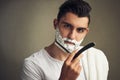 Be kinder to your skin. a handsome young man shaving with a straight razor.