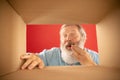 Be modest. Senior bearded man unpacking, opening carton box and looking inside. Delivery, surprise, gift, emotions