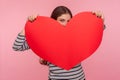 Be my Valentine! Portrait of flirtatious woman peeping out huge red paper heart with playful happy look