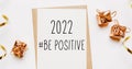 2022 be positive note with envelope, gifts and gold ribbon on white background