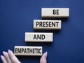 Be Present and Empathetic symbol. Concept words Be Present and Empathetic on wooden blocks. Businessman hand. Beautiful deep blue