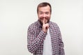 Be quiet! Portrait of cheerful bearded man making hush silence gesture with finger on his lips. white background