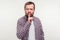 Be quiet! Portrait of strict serious bearded man making hush silence gesture with finger on lips. white background