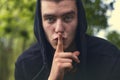 Portrait of a young man holding a finger to his mouth