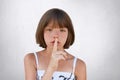 Be silent, hush! Adorable small kid showing silent sign asking to be noiseless as her little sister is sleeping. Freckled girl wit Royalty Free Stock Photo