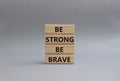 Be strong be brave symbol. Concept words Be strong be brave on wooden blocks. Beautiful grey background. Business concept. Copy