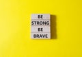 Be strong be brave symbol. Concept words Be strong be brave on wooden blocks. Beautiful yellow background. Business concept. Copy