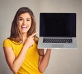 Be sure to bookmark this website. an attractive young woman holding a laptop with a blank screen against a grey Royalty Free Stock Photo