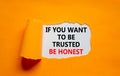 Be trusted and honest symbol. Concept words If you want to be trusted be honest on white paper on a beautiful orange background. Royalty Free Stock Photo