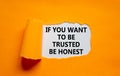 Be trusted and honest symbol. Concept words If you want to be trusted be honest on white paper on a beautiful orange background. Royalty Free Stock Photo