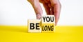 Be you, belong symbol. Businessman hand turns a cube and changes words `be you` to `belong`. Beautiful white and yellow backgr