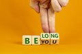 Be you, belong symbol. Businessman hand turns cubes and changes words `be you` to `belong`. Beautiful orange background. Busin