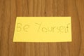 Be yourself handwrite on a yellow paper with a pen on a table