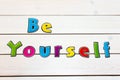 Be Yourself. Positive affirmation, statement. Bold neon letters on white washed table as background