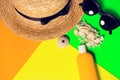 Beach accessories on a bright neon colorful background. A fragment of a straw hat and sea urchin shell , shells necklace, a bottle Royalty Free Stock Photo