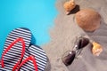 Beach accessories. Flip flops, glasses from the sun, shells and coconut on the sand of the sea. on a blue background. Royalty Free Stock Photo