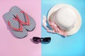 Beach accessories. Flip-flops and a summer hat with sunglasses on a bright pink and blue background. Top view Royalty Free Stock Photo