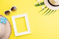 Beach accessories picture frame, sunglasses, starfish, beach hat and Green tropical leaves on yellow background for summer holiday