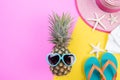 Beach accessories pineapple, sunglasses, flip flop, starfish beach hat and sea shell on pink and yellow background for summer Royalty Free Stock Photo