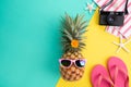 Beach accessories retro film camera, pineapple, sunglasses, flip flop starfish beach hat and sea shell on green and yellow Royalty Free Stock Photo