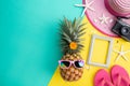 Beach accessories retro film camera, pineapple, sunglasses, flip flop starfish beach hat and sea shell on pink and yellow Royalty Free Stock Photo