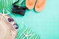 Beach accessories retro film camera, sunglasses, flip flop, starfish beach hat and sea shell on bright pastel green background for Royalty Free Stock Photo