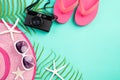 Beach accessories retro film camera, sunglasses, flip flop, starfish beach hat and sea shell on bright pastel green background for Royalty Free Stock Photo