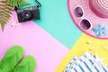 Beach accessories retro film camera, sunglasses, flip flop starfish beach hat and sea shell on pink and yellow background for Royalty Free Stock Photo