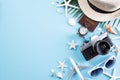 Beach accessories retro film camera, sunglasses, passport book, airplane, starfish beach hat and sea shell on blue pastel