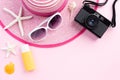 Beach accessories retro film camera, sunglasses starfish, beach hat and sea shell sunblock on sandy beach and pink background for Royalty Free Stock Photo