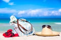 Beach accessories on sand for summer vacation concept. Bag, straw hat with sunglasses and red flip flops. White sand with amazing Royalty Free Stock Photo