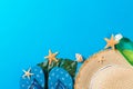 Beach accessories with straw hat and seashells on blue background top view with copy space Royalty Free Stock Photo