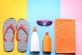 Beach accessories. Various creams, glasses, flip flops and on a colored background. Top view.