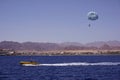 Beach activity: parasailing, high-speed boat pulls a man on a parachute. Sea and mountains on the background