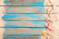 Op view of beach sand with shells, starfish on wood plank in blue sea