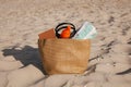 Beach bag with towel, book and sunscreen on sand