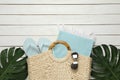 Beach bag with towel, flip flops and sunglasses on white wooden background, flat lay. Space for text Royalty Free Stock Photo