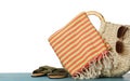 Beach bag with towel, slippers and sunglasses on light blue wooden surface against white background Royalty Free Stock Photo