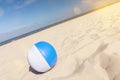 Beach ball on a beautiful beach in summer with scenic lens flare and tilted horizon