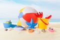 Beach ball and bucket with toys in sand on blue Royalty Free Stock Photo