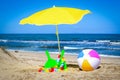 Beach ball, rackets and parasol by the sea Royalty Free Stock Photo