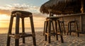 Beach Bar Sunset: Wooden Stools on Sandy Beach at Golden Hour Royalty Free Stock Photo