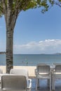 Beach bar terrace in the shade of the trees with a surfer zigzagging Royalty Free Stock Photo