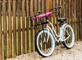 Beach bike parked against a fence with umbrellas in its basket Royalty Free Stock Photo