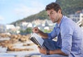 Beach, book and young man reading for knowledge or relaxing hobby on vacation or holiday. Travel, outdoor and handsome Royalty Free Stock Photo