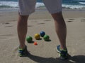 On a sunny California beach, a bocce player stands in front of the balls, planning his next move.