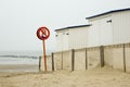 Warning for not swimming and wooden cabins on the beach. Royalty Free Stock Photo