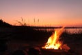 Beach Campfire on Lake. Red sky Superior at sunset as vacation concept Royalty Free Stock Photo